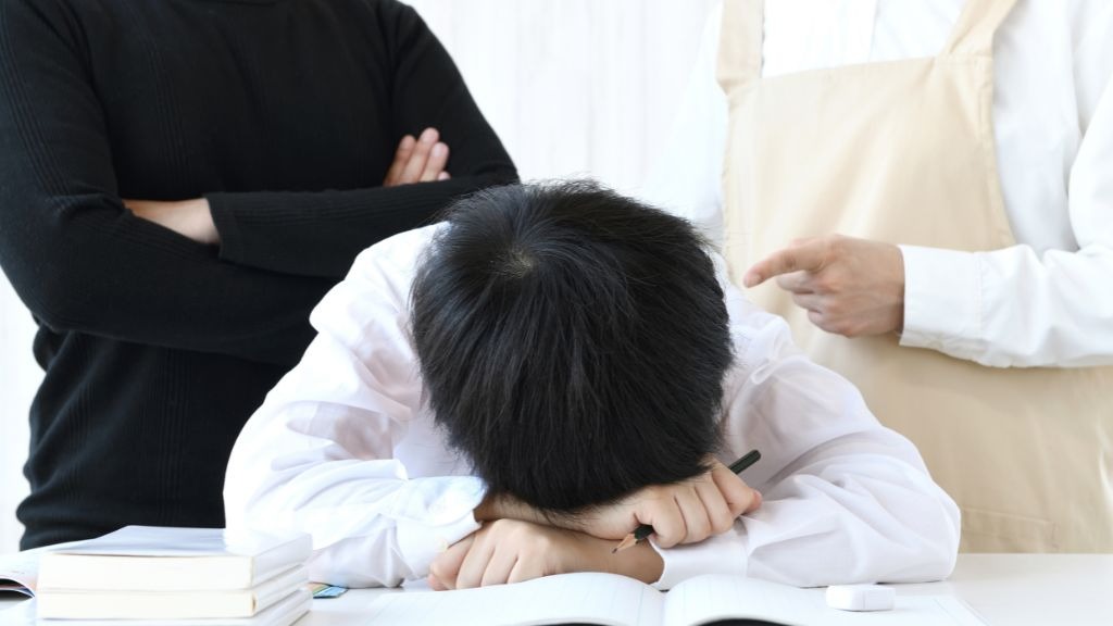 両親に問い詰められ突っ伏している男子中学生